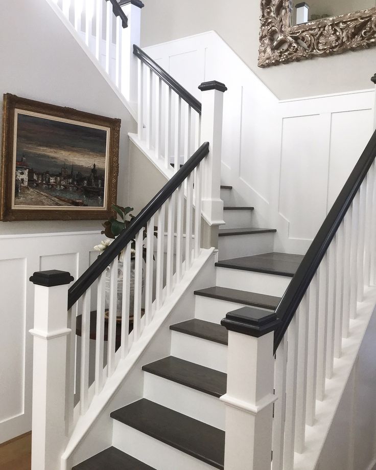 a white staircase with black handrails in a home's entryway area