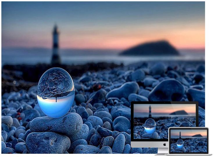 a crystal ball sitting on top of some rocks near the ocean with a lighthouse in the background