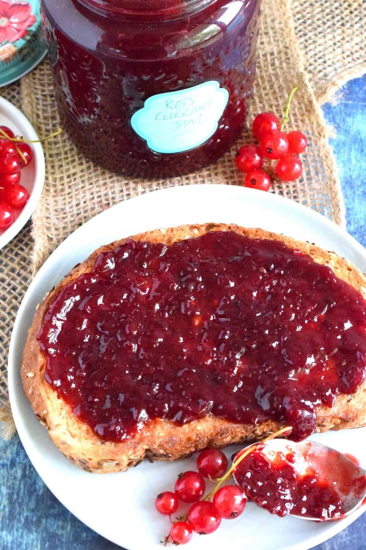 a piece of bread with jam on it sitting on a plate next to some berries