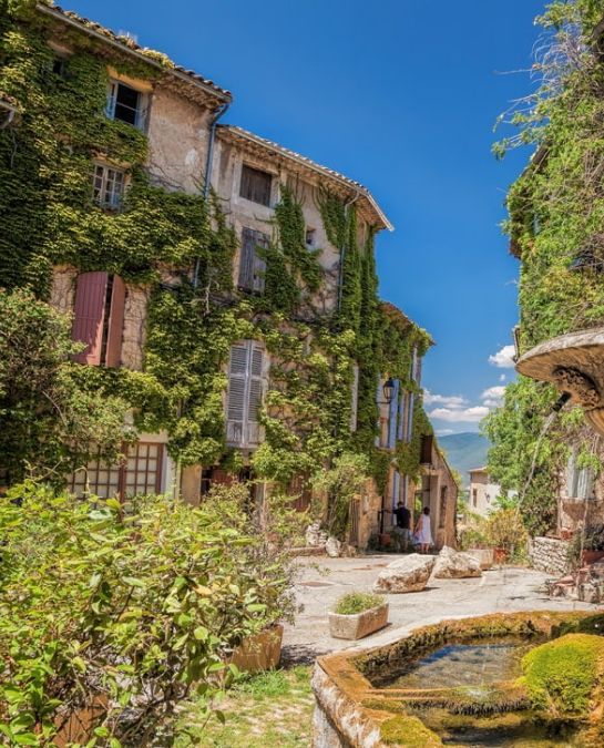 an old building with ivy growing on it's sides and a fountain in the middle