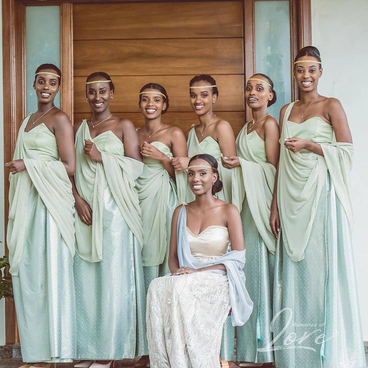 a group of women standing next to each other in front of a door wearing dresses