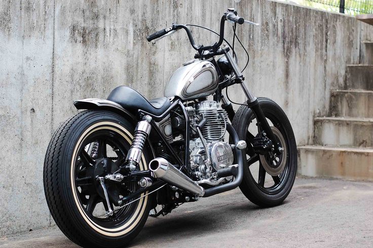 a silver motorcycle parked in front of a concrete wall with steps leading up to it