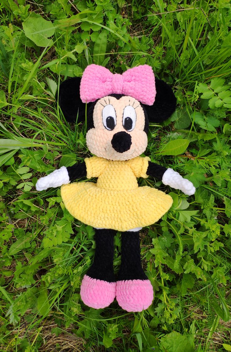 a crocheted minnie mouse doll laying in the grass