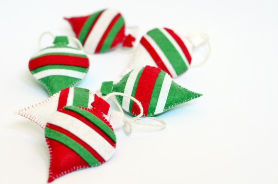 four red, green and white striped ornaments on a white table with string attached to them