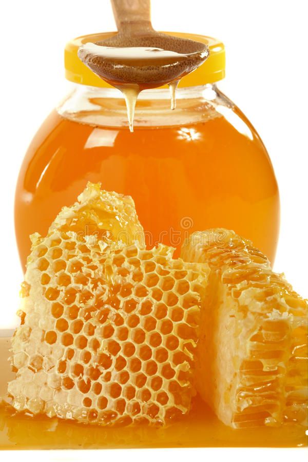 honey in a glass jar and some pieces on the table royalty images, stock photos