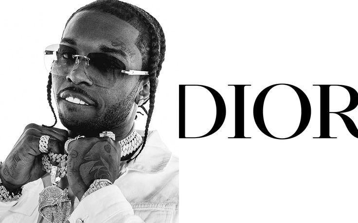 a man wearing glasses and a necklace with the word dior in front of him