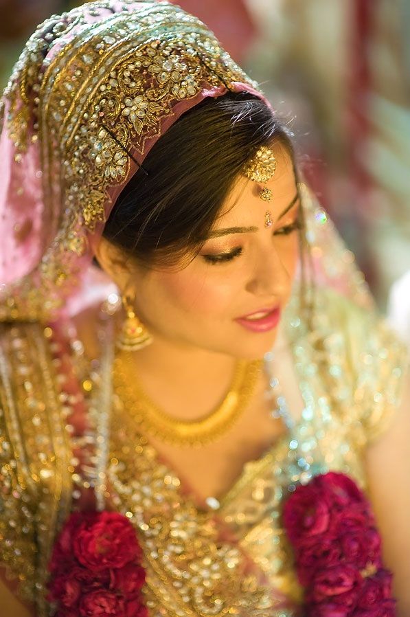 a woman wearing a gold and red outfit with flowers in her hair is looking down