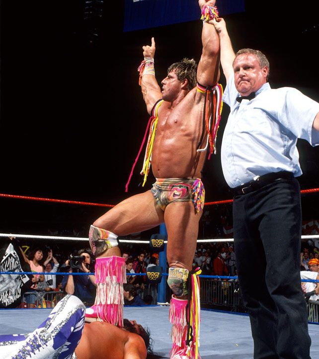 two men standing next to each other on top of a wrestling ring