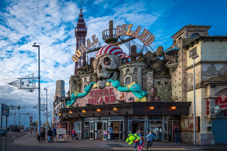 people are walking on the street in front of an amusement park