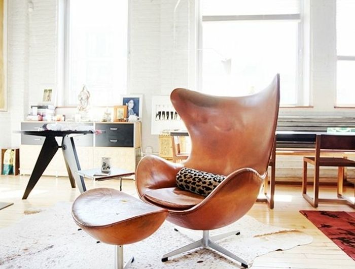 an egg chair and ottoman in the middle of a room