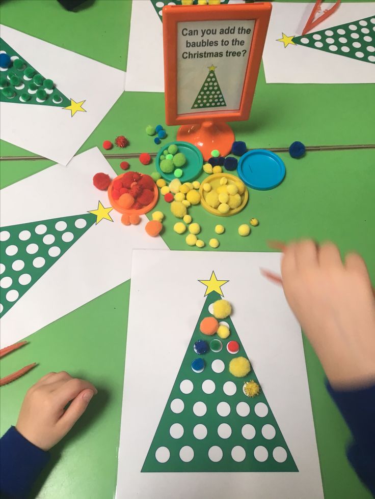 two children are making christmas trees out of construction paper and colored pencils on the table