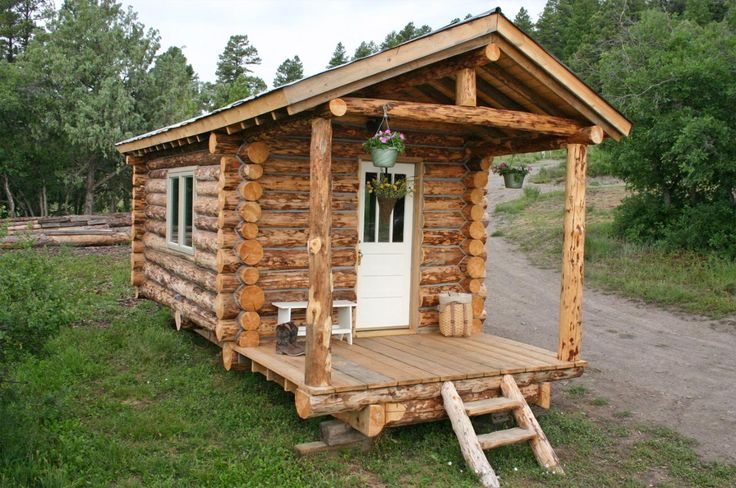 a small log cabin sitting on top of a lush green field