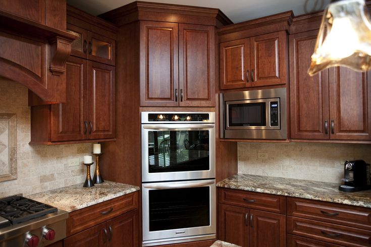 a kitchen with wooden cabinets and stainless steel oven, microwave and stove top hoods