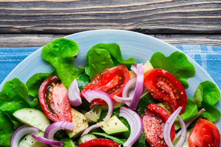 a salad with tomatoes, cucumbers, onions and lettuce on a plate