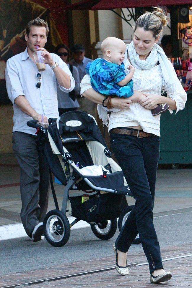 a man and woman walking down the street with a baby in a stroller next to them