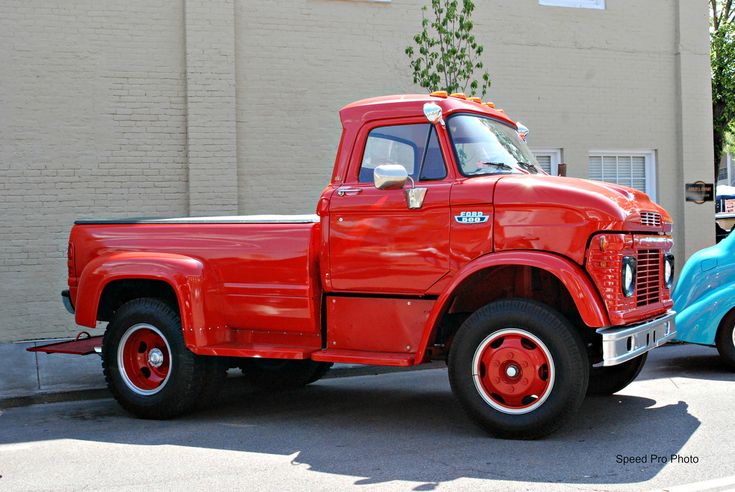 an old red and blue truck parked next to each other in front of a building