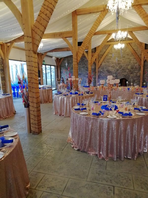 a banquet hall with tables and chairs covered in pink tablecloths, blue place settings and chandeliers