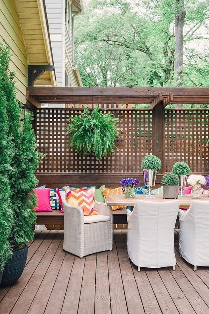 a wooden deck with white wicker furniture and potted plants