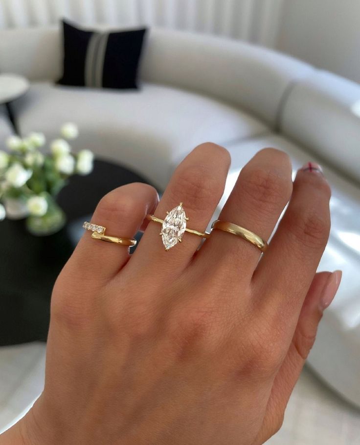 a woman's hand with two gold rings and a diamond ring on her finger