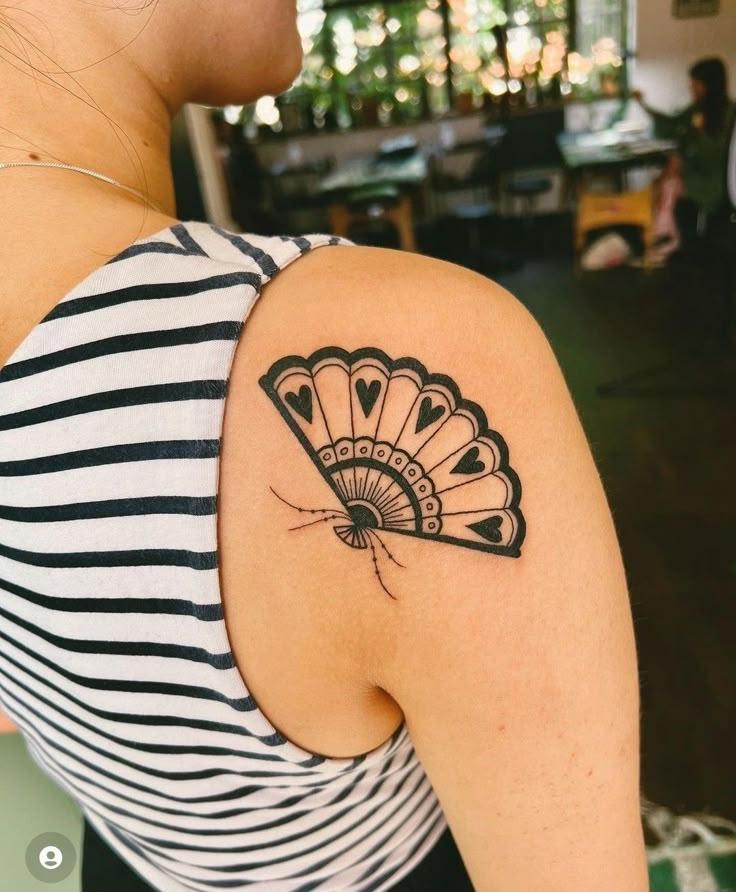 a woman with a fan tattoo on her shoulder