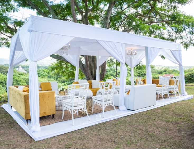 a white tent set up with yellow and white furniture