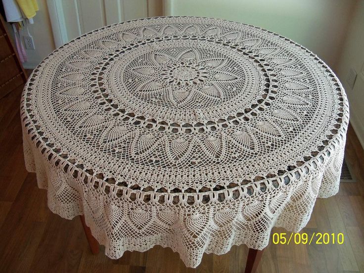 a crocheted tablecloth on a wooden table in a room with hardwood floors