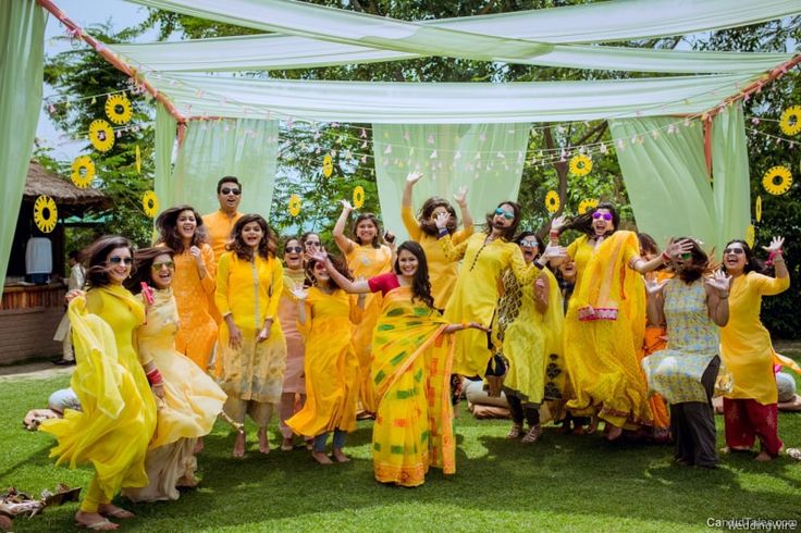 a group of women in yellow dresses posing for the camera with their arms up and hands raised