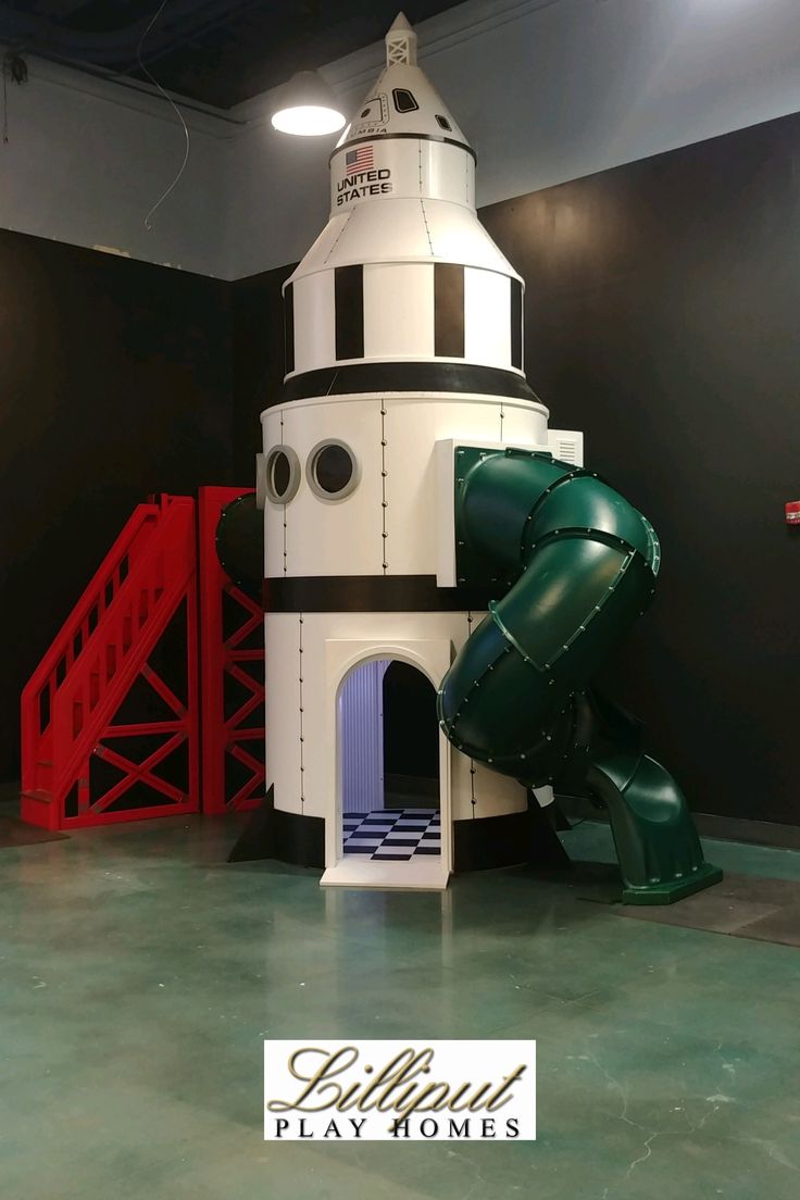 a large white and black tower with a slide in it's center, surrounded by red stairs