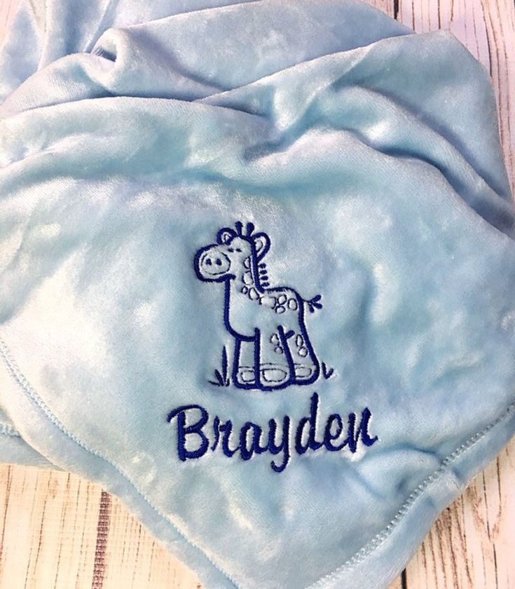 a blue blanket with a giraffe embroidered on the side and name that says, brayden