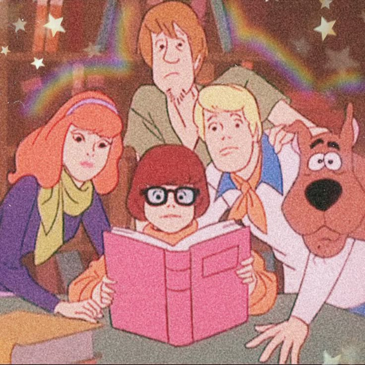 the scooby gang is reading a book with their dog in front of them