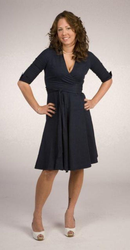 a woman standing with her hands on her hips and arms on her hips, wearing a black dress