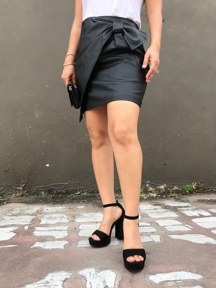 This Lead the Way Black Mini Skirt is a must have! The bow wrap detail will instantly make you want to dance, party, or go out for dinner with a special someone or with friends. Any stylish shoe matches perfectly with this beautiful black skirt. plus, the tops you can wear with this faux leather skirt are endless. A staple piece every closet should have! Faux Leather Skirt with hidden back zipper 100% Polyester Measurements Small - Length waist to hem 17", Waist 24" Medium- Length waist to hem 1 Black Mini Skirt For Summer Cocktail, Chic Pencil Skirt For Party Season, Chic Pleated Party Mini Skirt, Holiday Black Mini Skirt, Black Summer Skirt With Bow Detail, Black Mini Skirt For Cocktail Party Season, Chic Lined Mini Skirt For Party, Black Skirt For Party Season, Chic Holiday Skirt For Night Out