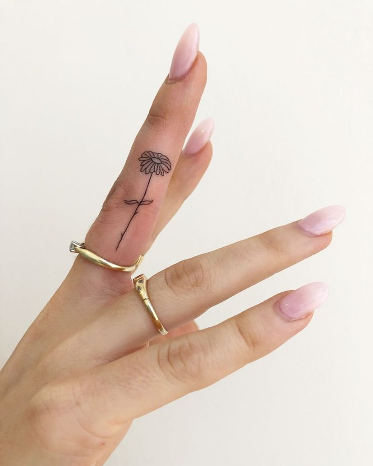 a woman's hand with a small tattoo on her left thumb and a tiny ring in the middle