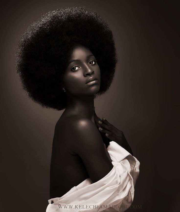 a woman with an afro standing in front of a dark background