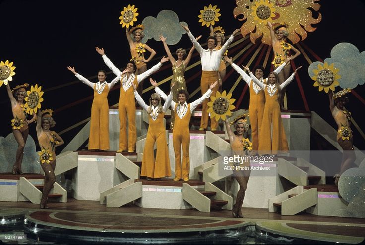 an image of a group of people on stage with sunflowers in their hands