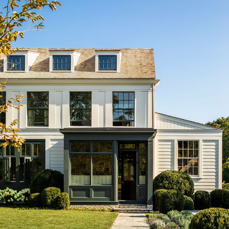 a white house with lots of windows and bushes