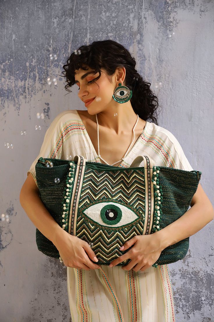 Keeping up with the trendiest color of the season, say hello to your favourite Evil Eye Embellished Tote, now here in an Evergreen Forest color. A show-stopping glory for when all eyes must be on you. This tote bag is perfect for everyday use and for special occasions too! It features a hand beaded evil eye in front for protection, and is hand-embellished with beads and sequins for a touch of glamour. The double shoulder straps are adorned with lace detail, and the bag has a magnetic button clos Green Shoulder Bag For Summer Parties, Green Summer Party Shoulder Bag, Green Summer Party Bags, Green Shoulder Bag For Shopping, Green Tote Shoulder Bag For Party, Green Bohemian Shoulder Bag For Shopping, Chic Embellished Green Bags, Chic Green Embellished Bags, Green Embellished Rectangular Shoulder Bag