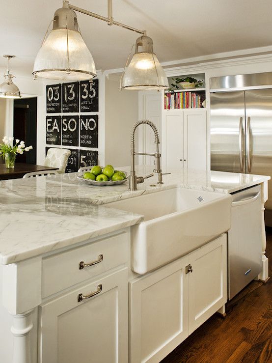 a large kitchen with white cabinets and marble counter tops, along with an island in the middle