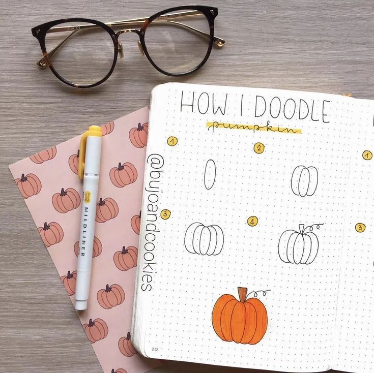 an open planner with pumpkins on it next to eyeglasses and a pen