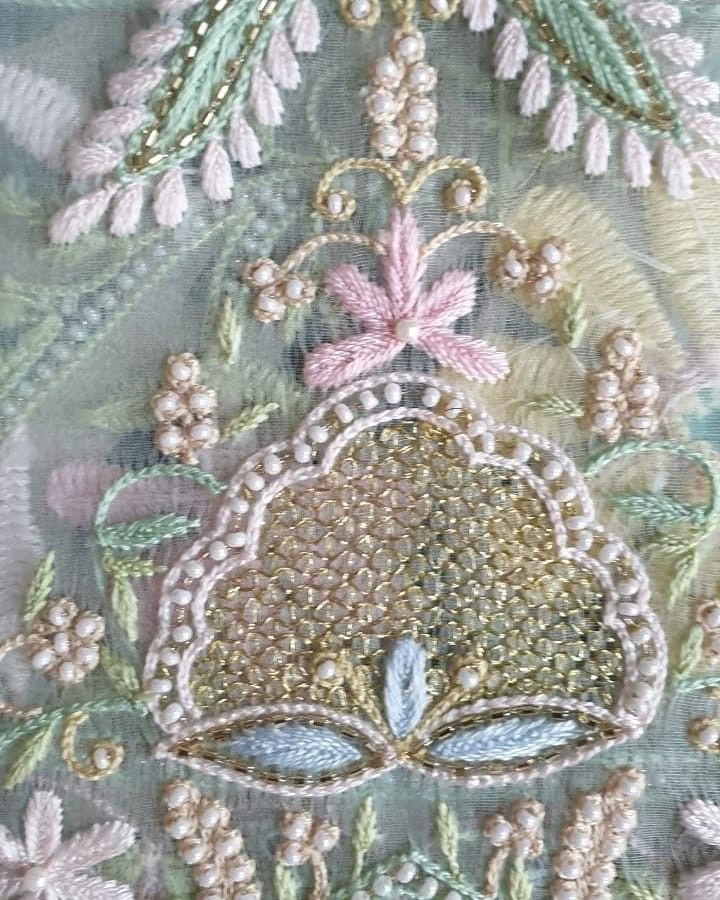 an embroidered piece with flowers and leaves on it's side, in pastel colors