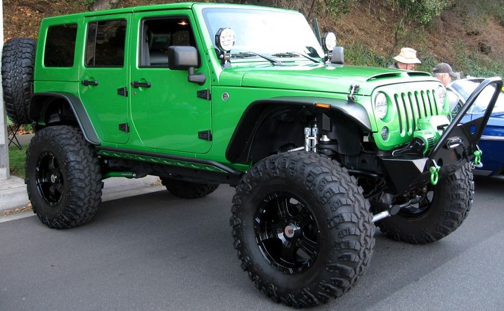 a green jeep parked next to a blue car