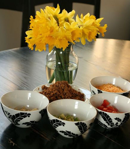 four bowls on a table with yellow flowers in the vase and other dishes around them