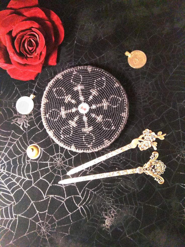 there is a rose on the table with scissors and beads