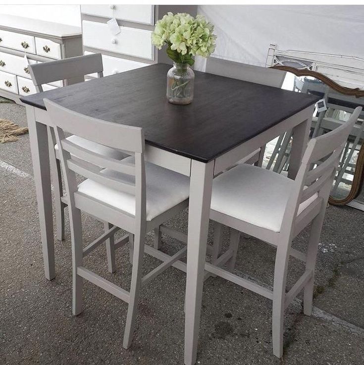 a table with four chairs and a vase filled with flowers on top of the table