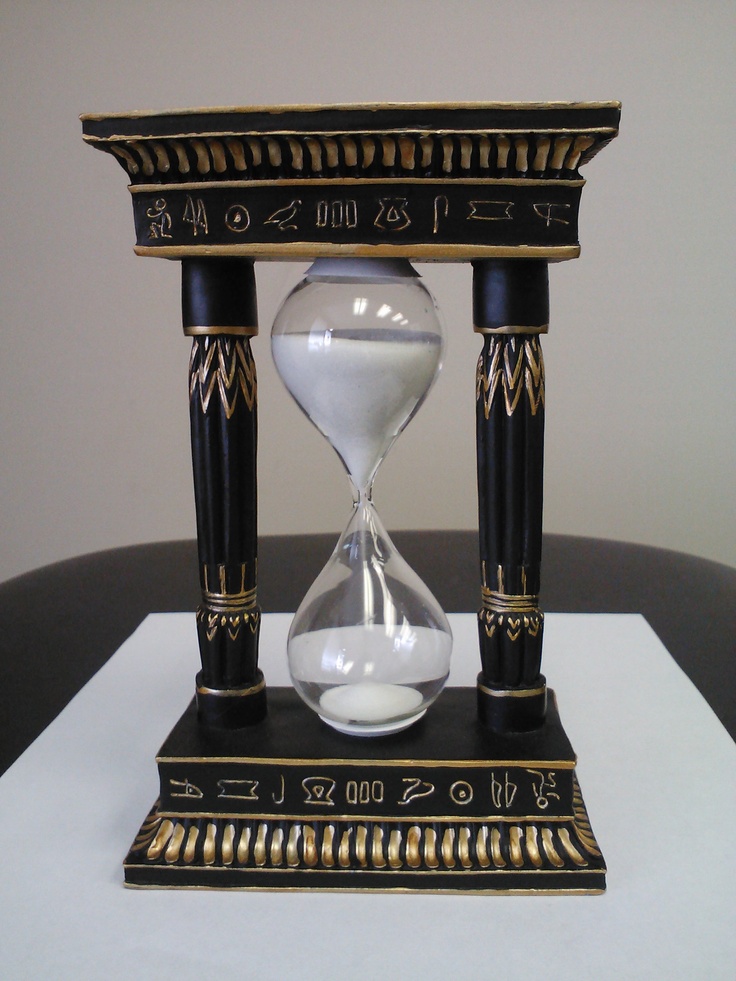 an hourglass sitting on top of a table next to a black and gold clock