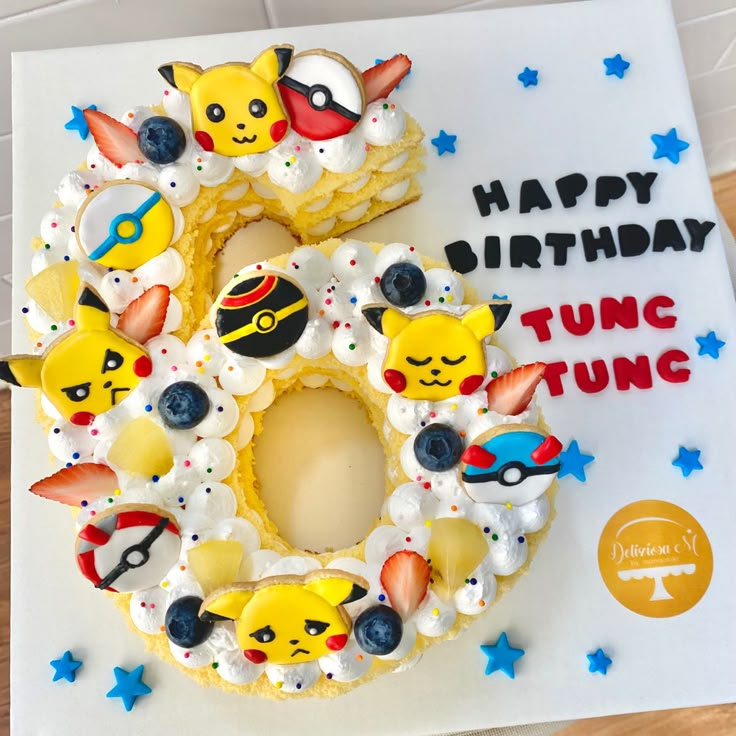 a pokemon themed birthday cake on top of a white sheet with the number 3 surrounded by pikachu and other cartoon characters