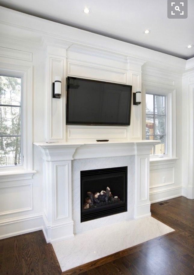 a fireplace with a flat screen tv mounted on it's mantle in a living room