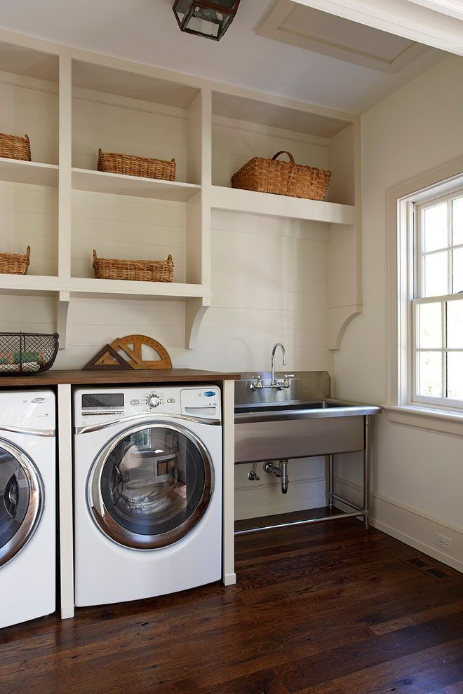 a washer and dryer in a small room with open shelving on the wall