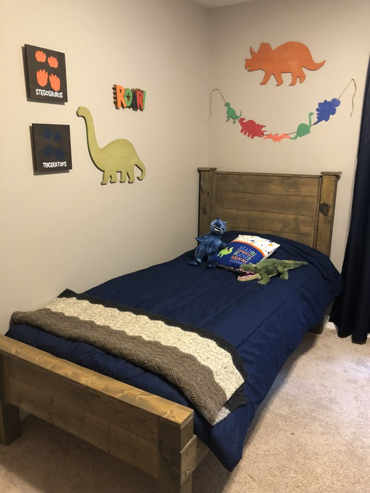 a child's bedroom with blue bedding and dinosaur wall art on the walls