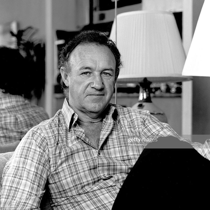 black and white photo of man sitting on couch in living room with lamp next to him